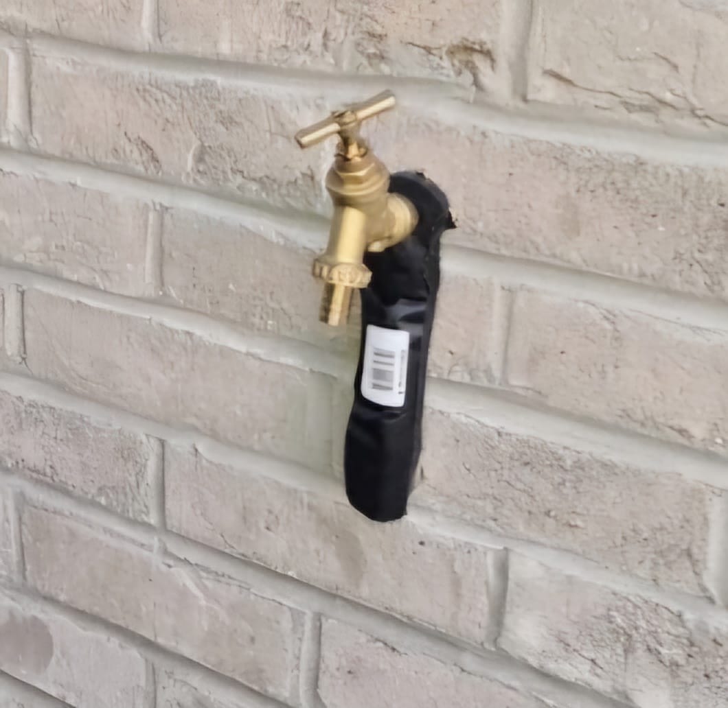 JHDS outdoor tap installation close-up — brass tap fitted to wall with black insulation lagging covering the pipe